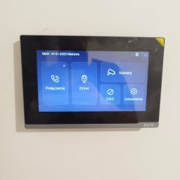 LANOPTIC - Panel sterowania wideodomofonu 'Kenik' z dotykowym ekranem. Widoczne opcje: połączenie, drzwi, kamery, DND i ustawienia. Na ekranie data: 01-01-2023.