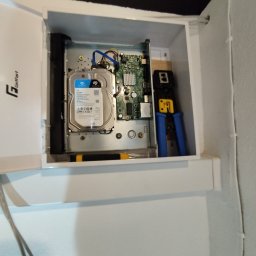 LANOPTIC - Wnętrze szafki z dyskiem twardym Seagate SkyHawk, płytą główną i narzędziem do zaciskania kabli, prawdopodobnie podczas montażu systemu monitoringu.