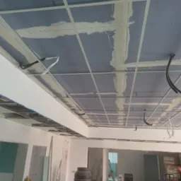 Sufit z płyt gipsowo-kartonowych w trakcie montażu, widoczne profile i częściowo zaszpachlowane łączenia. Prace wykończeniowe w nowym wnętrzu.