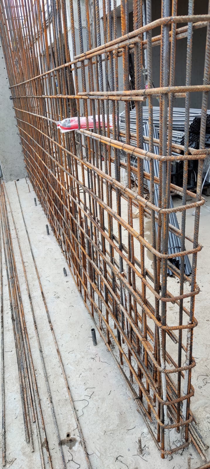 Siatka zbrojeniowa ze stalowych prętów, przygotowana do zalania betonem, widoczna z bliska, z detalami wiązań i prętów wystających z posadzki.