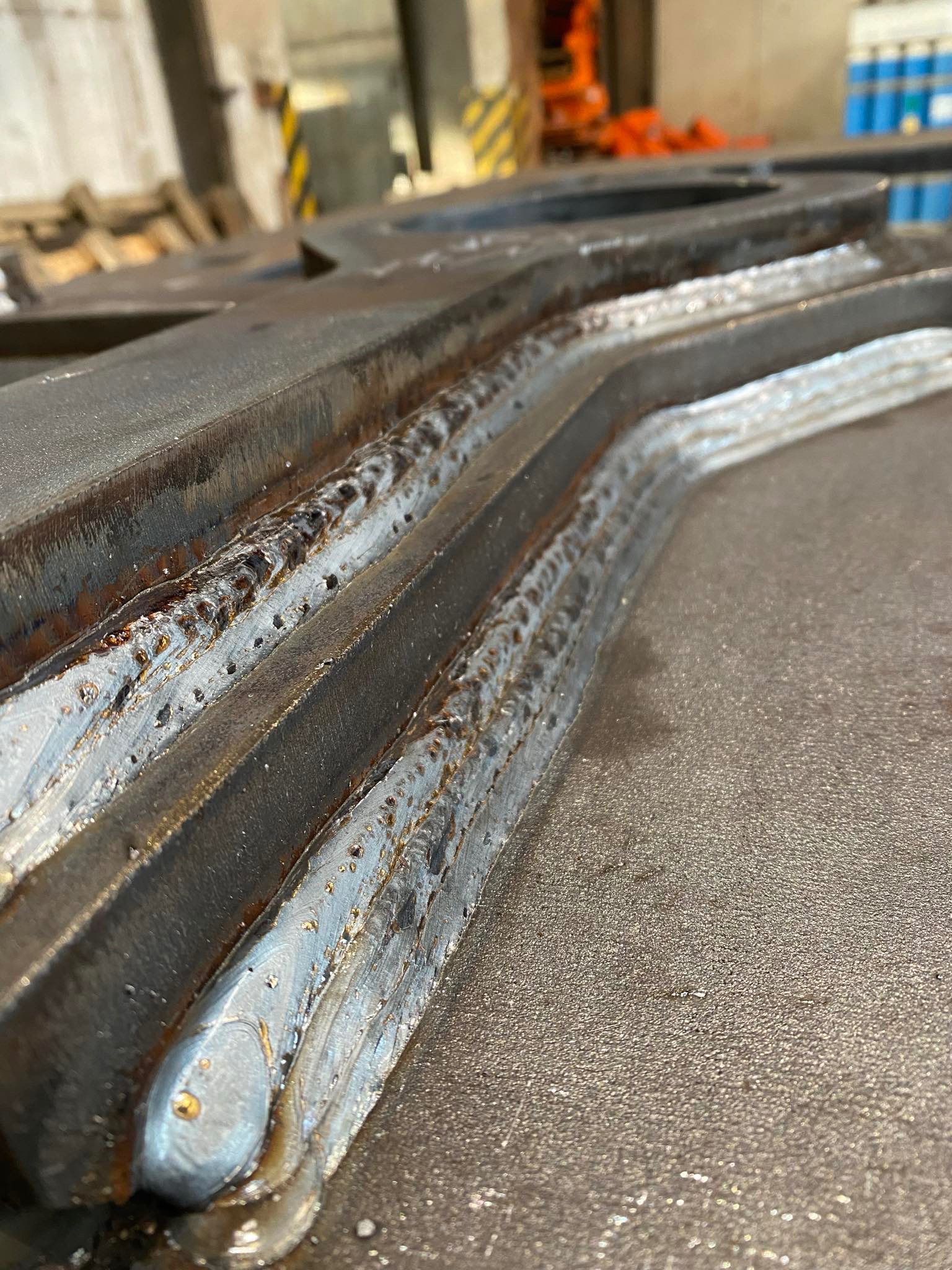 Metalowa konstrukcja po spawaniu, widoczne spoiny i obróbka krawędzi. Szlifowana powierzchnia z widocznymi detalami procesu.