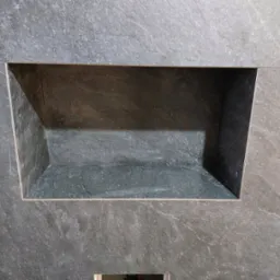 Wnęka wykończona szarą, kamienną okładziną, z widocznymi fugami. Minimalistyczny design w łazience, podkreślony przez precyzyjne ułożenie płytek i subtelne oświetlenie.