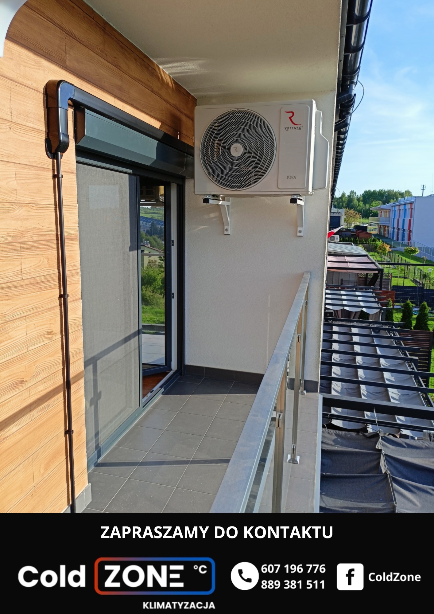 Klimatyzator Rotenso Hiro Series, zamontowany na balkonie z szarymi płytkami i metalową barierką. Widok na zieleń i zabudowania w tle.