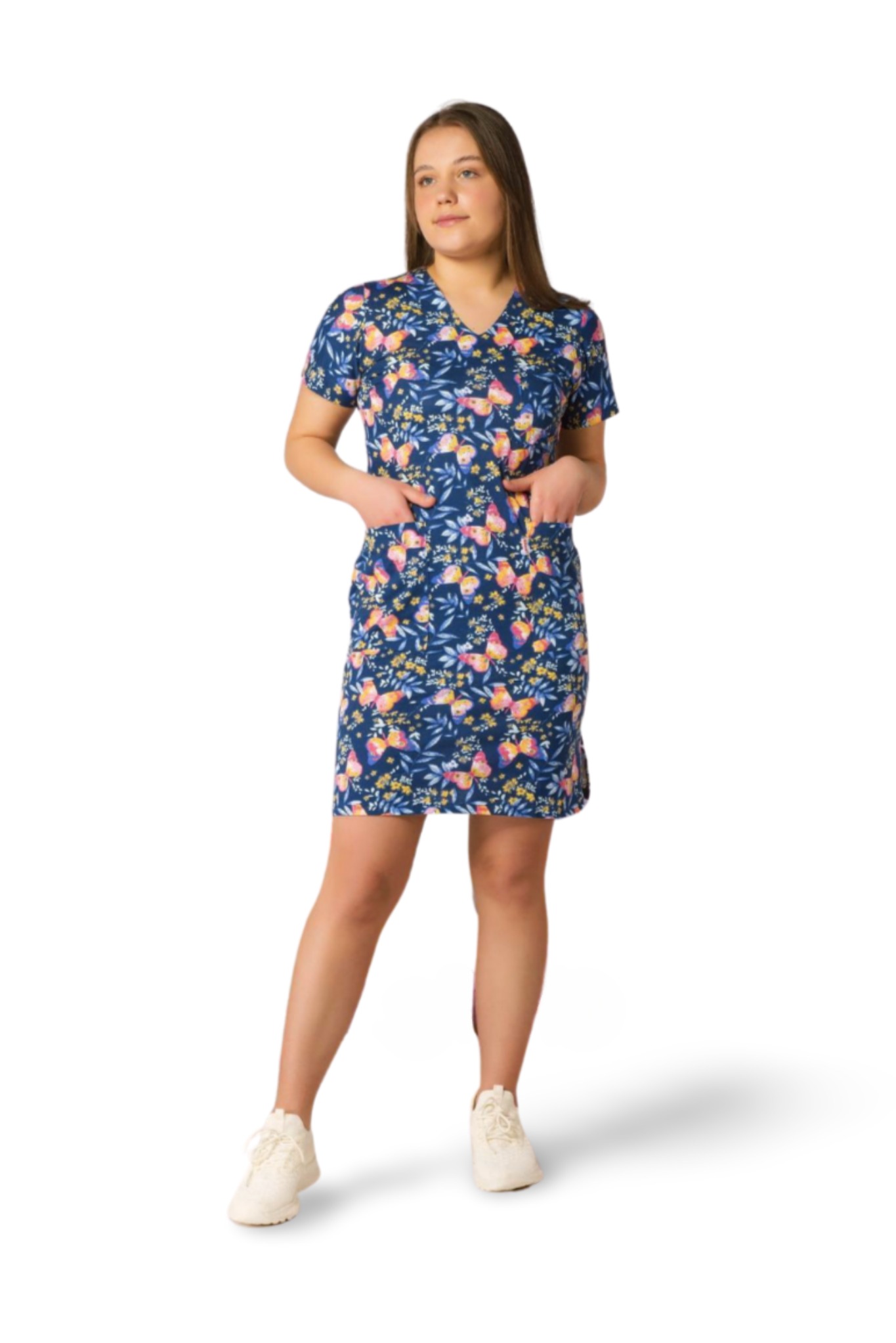 Portret kobiety w niebieskiej sukience w motyle i kwiaty, z rękami w kieszeniach, na białym tle. Całość w jasnej tonacji, z delikatnym cieniem.