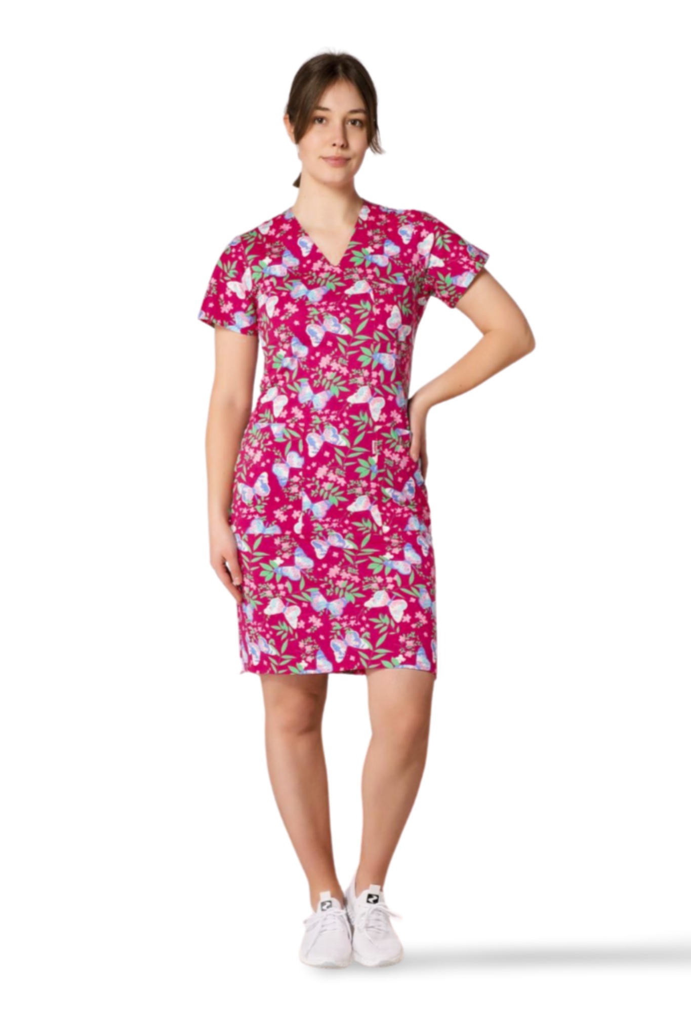 Kobieta w różowej sukience z motywem motyli i kwiatów. Krótki rękaw, krój dopasowany. Białe sportowe buty. Całość na białym tle. Jasne oświetlenie.