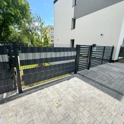Denys Kokoshko Service - Nowoczesna brama wjazdowa i furtka z metalowymi panelami w kolorze grafitu i szarości, na tle jasnego budynku i brukowanej nawierzchni.