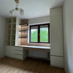 Nowoczesny pokój z zabudową meblową: białe szafy z półkami i biurko z drewnianym blatem pod oknem, oświetlenie punktowe, drewniana podłoga. Minimalistyczny design.