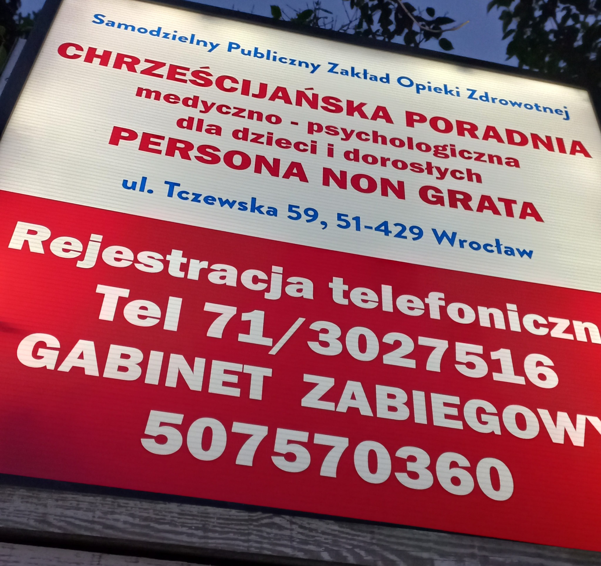 Szyld Chrześcijańskiej Poradni medyczno-psychologicznej Persona Non Grata we Wrocławiu, z numerem telefonu i adresem. Tablica informacyjna z nazwą gabinetu.