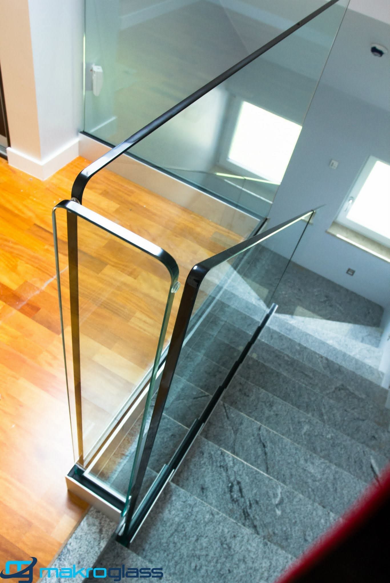 Nowoczesna balustrada szklana ze stali nierdzewnej, widok z góry na schody z szarego kamienia i drewnianą podłogę. Minimalistyczny design, jasne wnętrze.