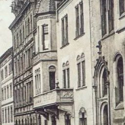 Kancelaria Adwokacka Adwokat Arkadiusz Malak Sprawy rodzinne o rozwód alimenty kontakty Sprawy majątkowe Nieruchomości Sprawy karne - Czarno-biała, stara pocztówka przedstawia kamienice z balkonami i zdobieniami architektonicznymi wzdłuż ulicy. Widoczne detale fasad i okien.