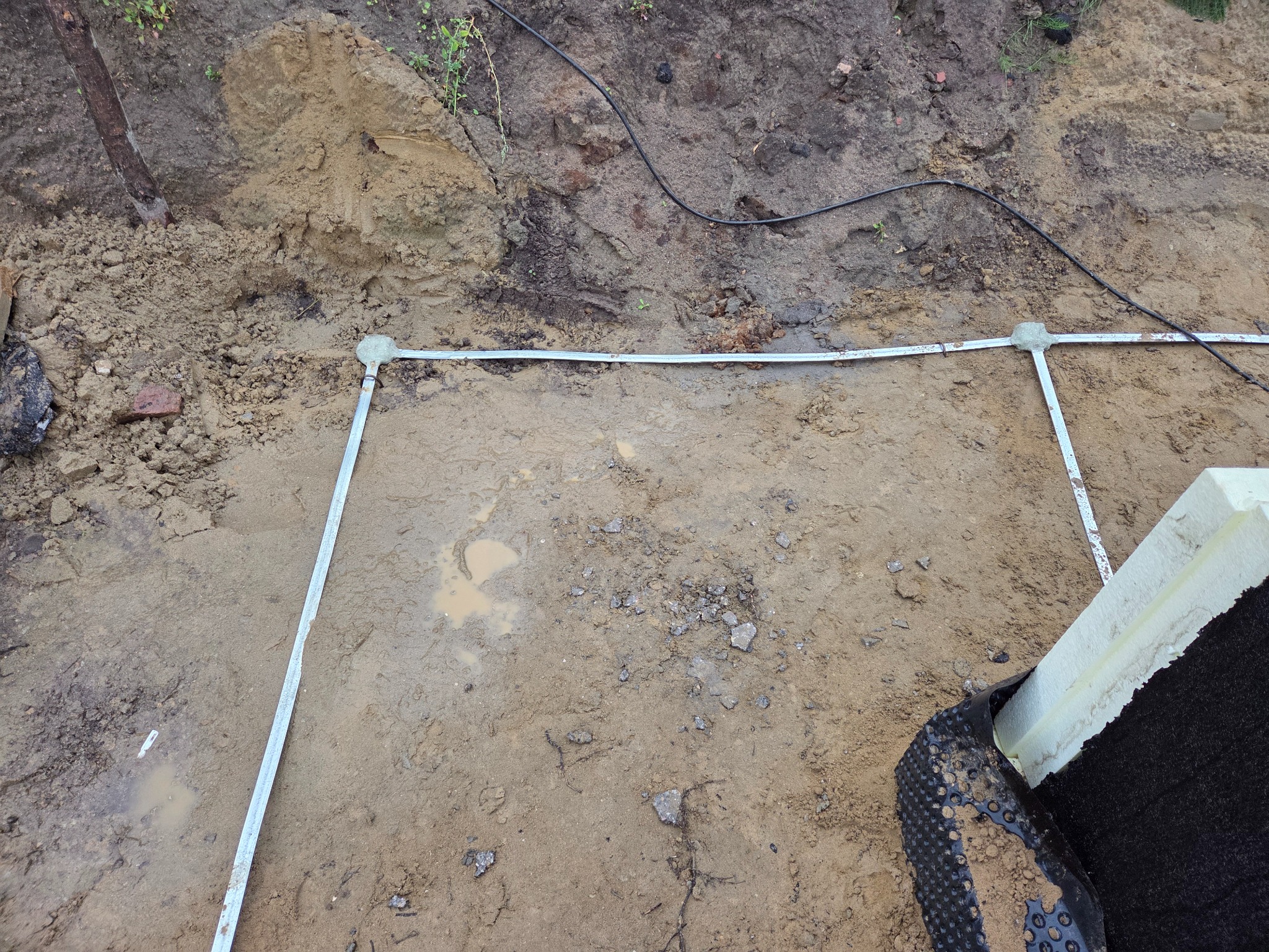 Wytyczony teren pod fundamenty z użyciem profili i sznurka. Widoczne elementy izolacji pionowej fundamentów.