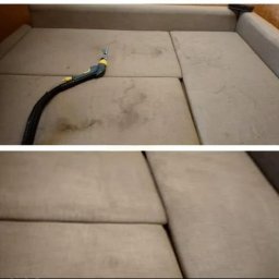 LEXTAN ANATOLII CHEREDNYCHENKO - Fragment sofy z widocznymi plamami i urządzeniem do czyszczenia tapicerki, prezentujący proces usuwania zabrudzeń. Dolna część pokazuje czystą powierzchnię.