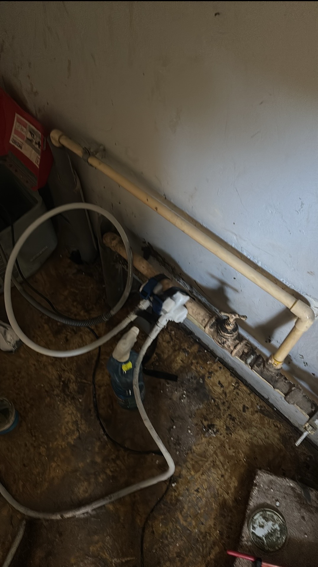 Instalacja wodna z rurami i zaworami w piwnicy w Łabiszynie, widoczne narzędzia hydrauliczne. Prace instalacyjne w trakcie realizacji.