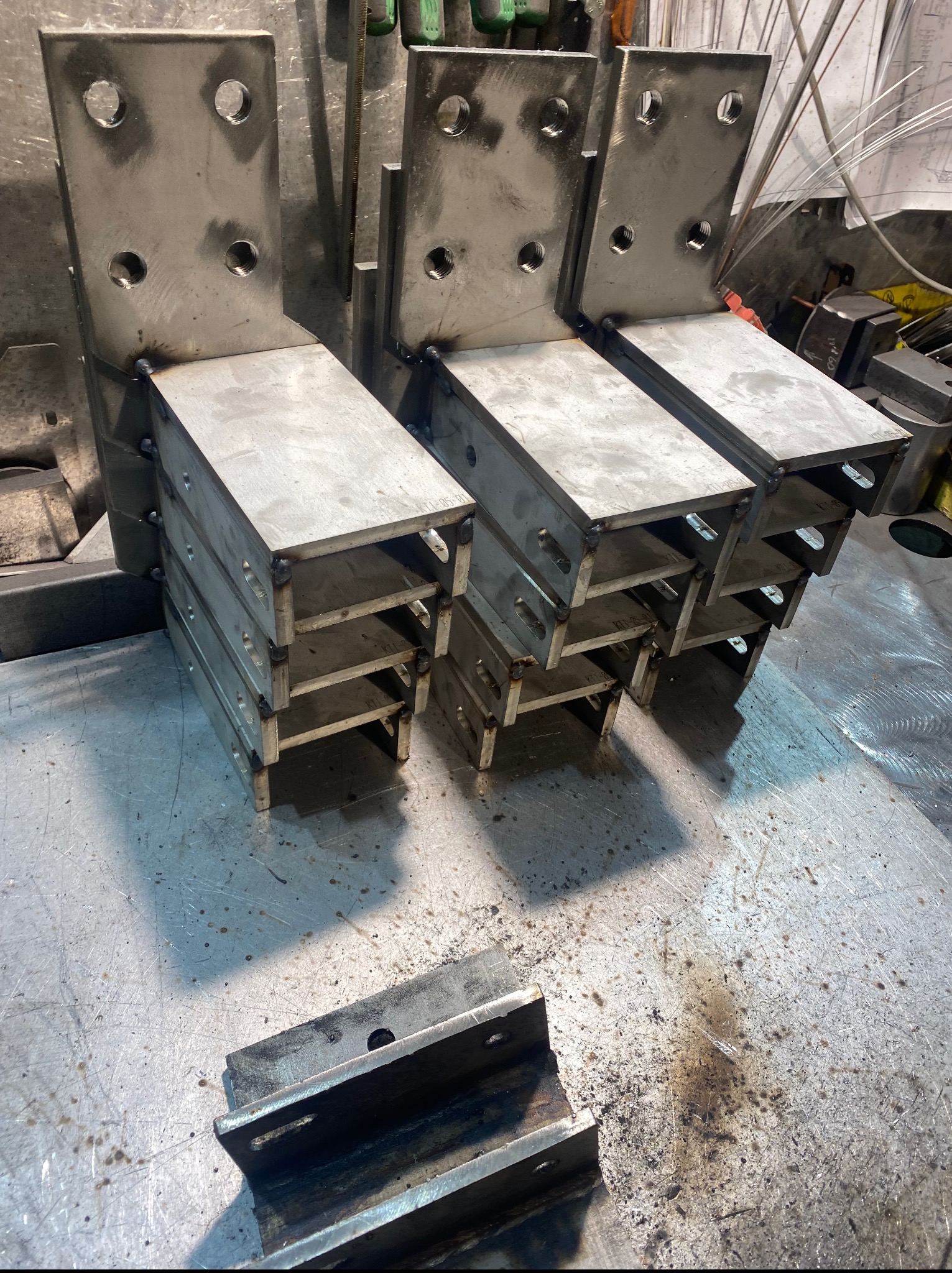 Metalowe elementy konstrukcyjne po spawaniu, widoczne spoiny, otwory montażowe. Praca ślusarska z Wołomina, detale z bliska, surowy metal, warsztatowy charakter.