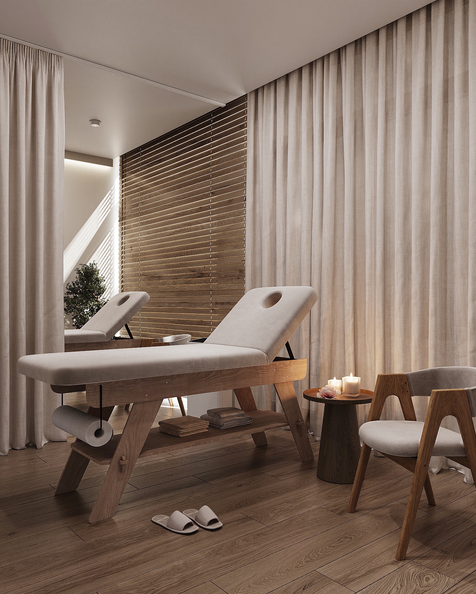 Jasne wnętrze gabinetu masażu z dwoma drewnianymi leżankami, krzesłem i stolikiem ze świecami, zasłonięte żaluzje i zasłony, drewniana podłoga, kapcie.