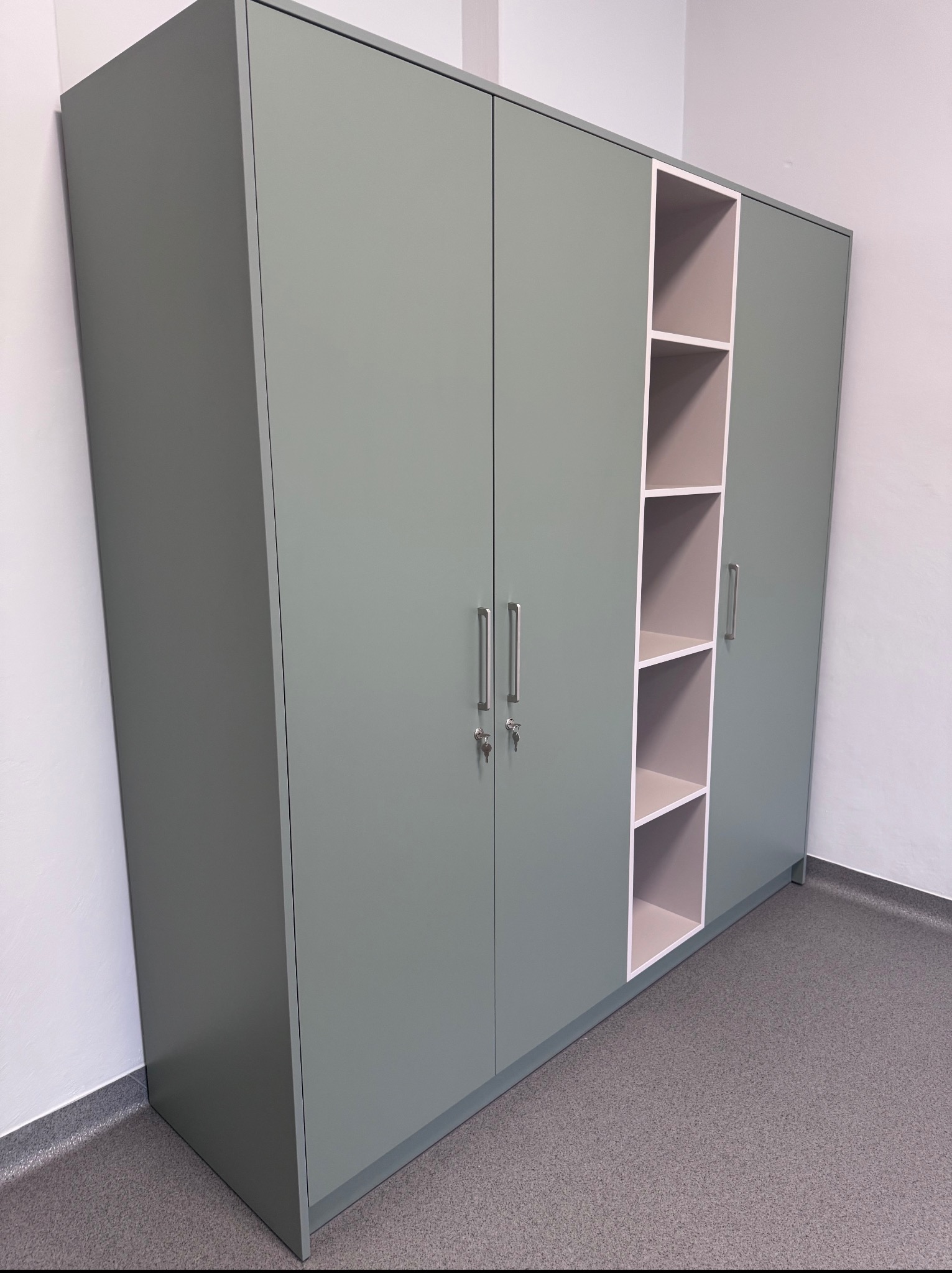 Szara szafa biurowa z półkami, metalowe uchwyty, zamykana na klucz, widok z boku, szara podłoga, białe ściany, minimalistyczny design.