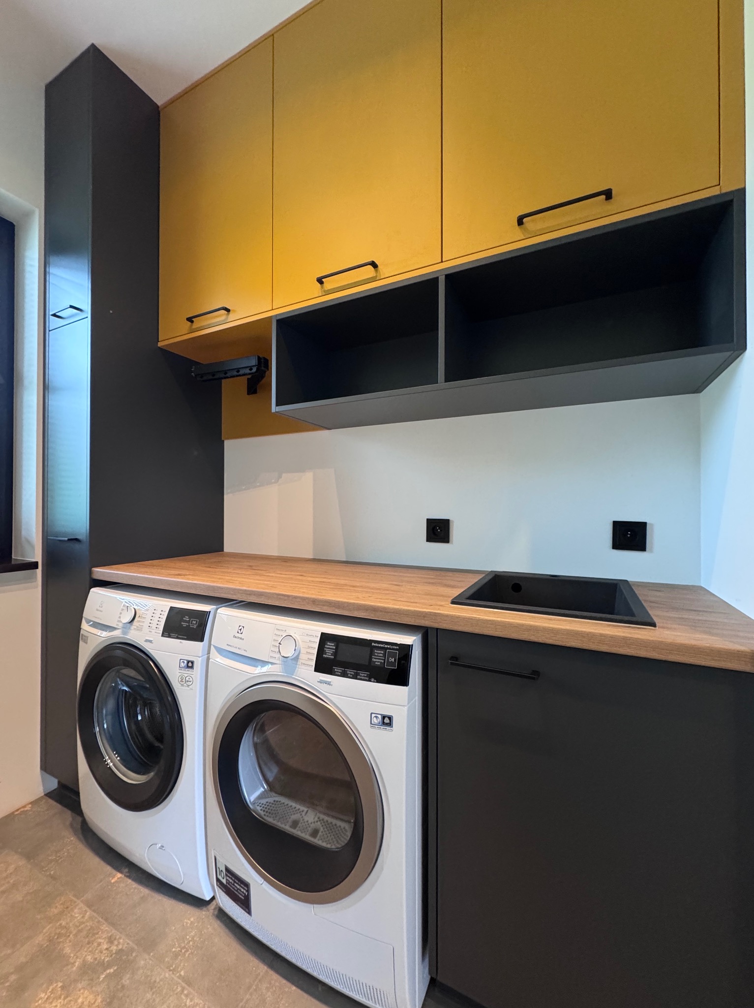 Zabudowa pralni, w słupku ukryty komin, a pod wiszacymi szafkami funkcjonalny rozkładany wieszaczek.