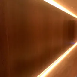 Drewniana ściana z podświetleniem LED wzdłuż górnej i dolnej krawędzi, tworząc efektowny wystrój wnętrza. Ciepłe światło podkreśla strukturę drewna.