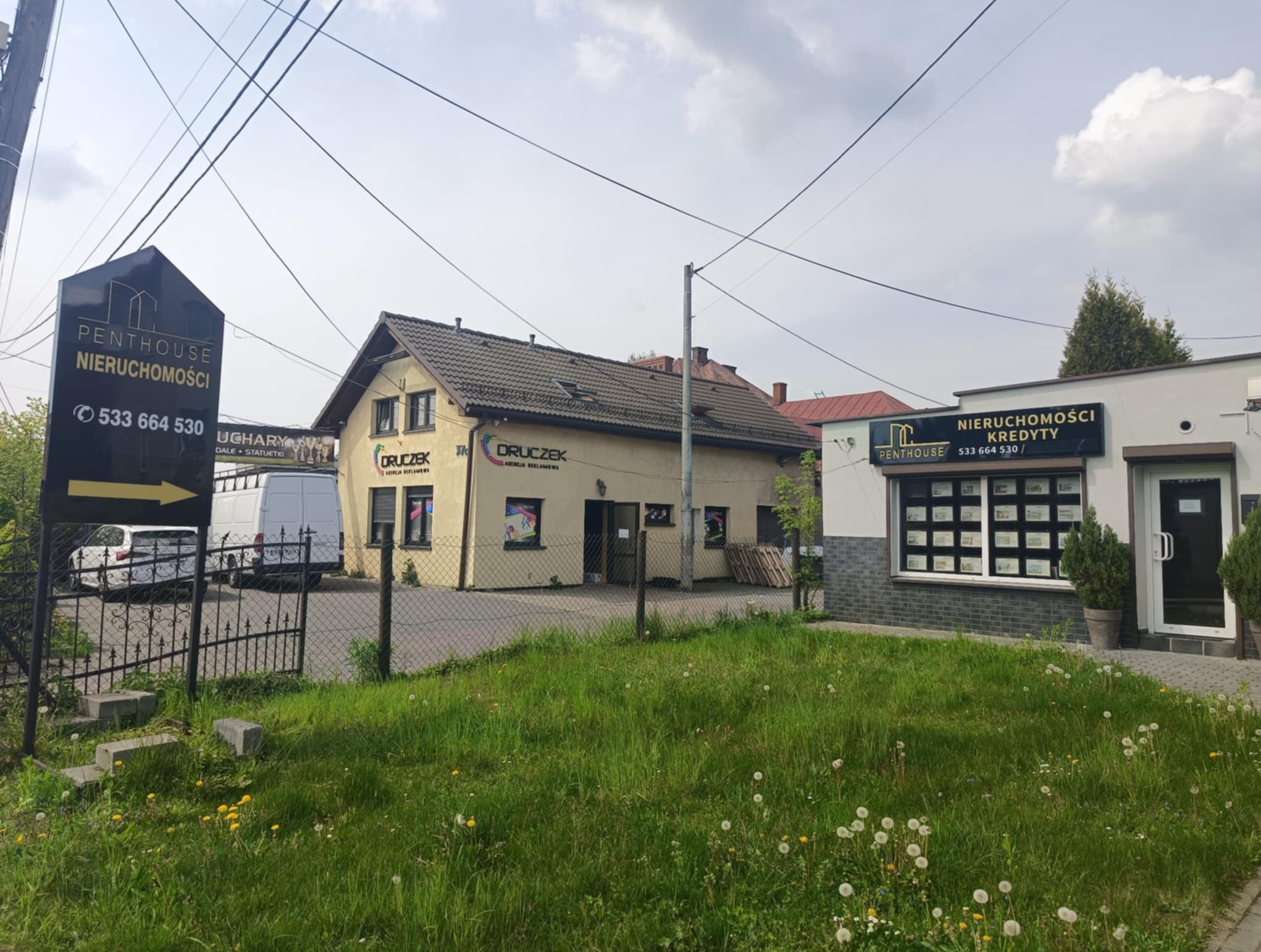 Siedziba agencji nieruchomości Penthouse w Jastrzębiu-Zdroju. Widoczny budynek z reklamą i tablica informacyjna z numerem telefonu.