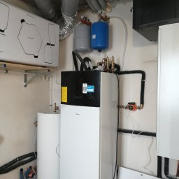 GREEN PLANET INSTALACJE - Zmontowana instalacja z pompą ciepła Daikin, zbiornikiem i orurowaniem w kotłowni. Widoczne elementy wentylacji i osprzęt.