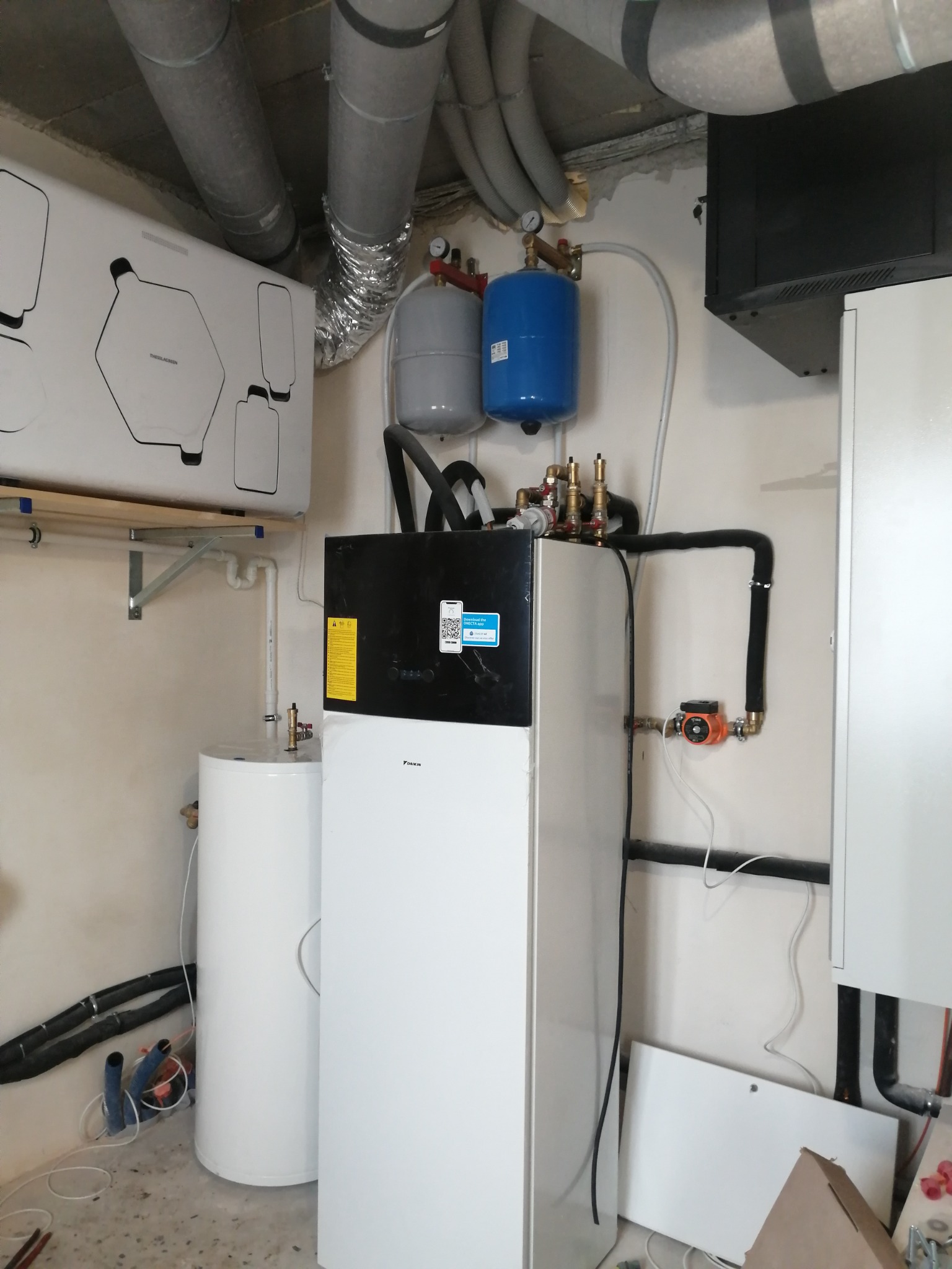 Zmontowana instalacja z pompą ciepła Daikin, zbiornikiem i orurowaniem w kotłowni. Widoczne elementy wentylacji i osprzęt.