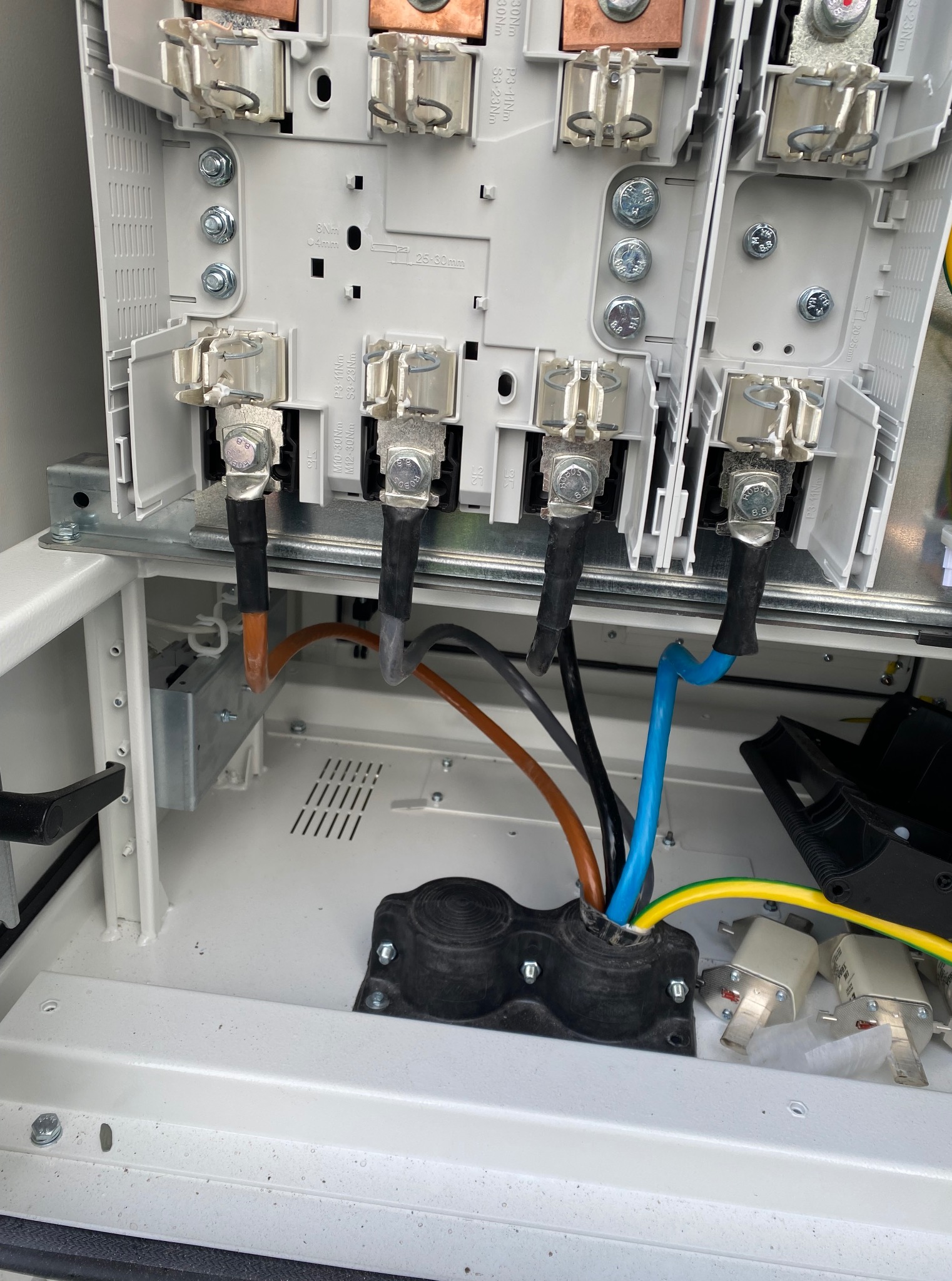 Wnętrze skrzynki elektrycznej z podłączonymi przewodami o różnych kolorach. Widoczne złącza, śruby i elementy montażowe. Instalacja w trakcie prac.