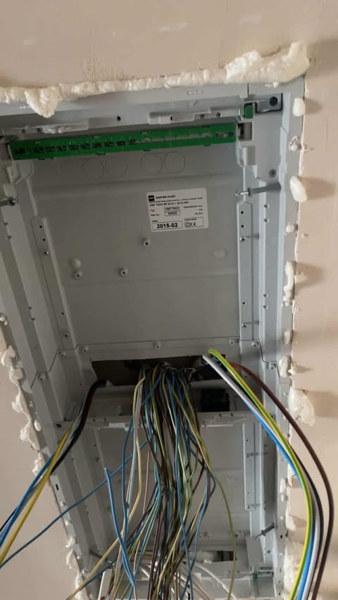 Rozdzielnica elektryczna zamontowana w suficie, zabezpieczona pianką montażową, z widocznymi przewodami elektrycznymi.