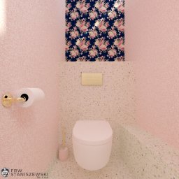 Joanna Staniszewska - Różowa łazienka z toaletą w stylu retro. Kwiatowa tapeta nad spłuczką, złota armatura i mozaika na ścianach tworzą unikalny design wnętrza.