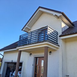 Paweł Otta - Dom z balkonem zabezpieczonym nowoczesną, poziomą konstrukcją. Ujęcie z dołu, podkreślające architekturę budynku i minimalistyczny design.