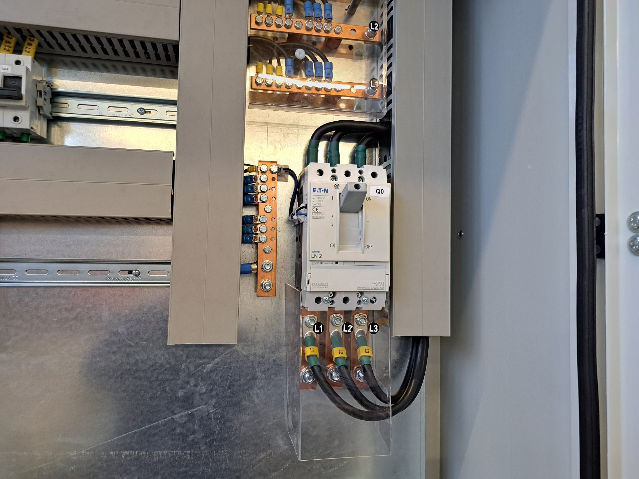 Rozdzielnica elektryczna Eaton z widocznymi bezpiecznikami, przewodami L1, L2, L3 i listwami zaciskowymi. Widoczne elementy montażowe Weidmuller.