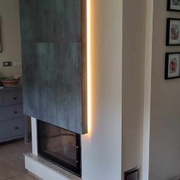 PCH usługi remontowo-budowlane - Nowoczesny kominek z szarymi płytami i pionowym oświetleniem LED. Estetyczne wykończenie wnętrza z dbałością o detale.