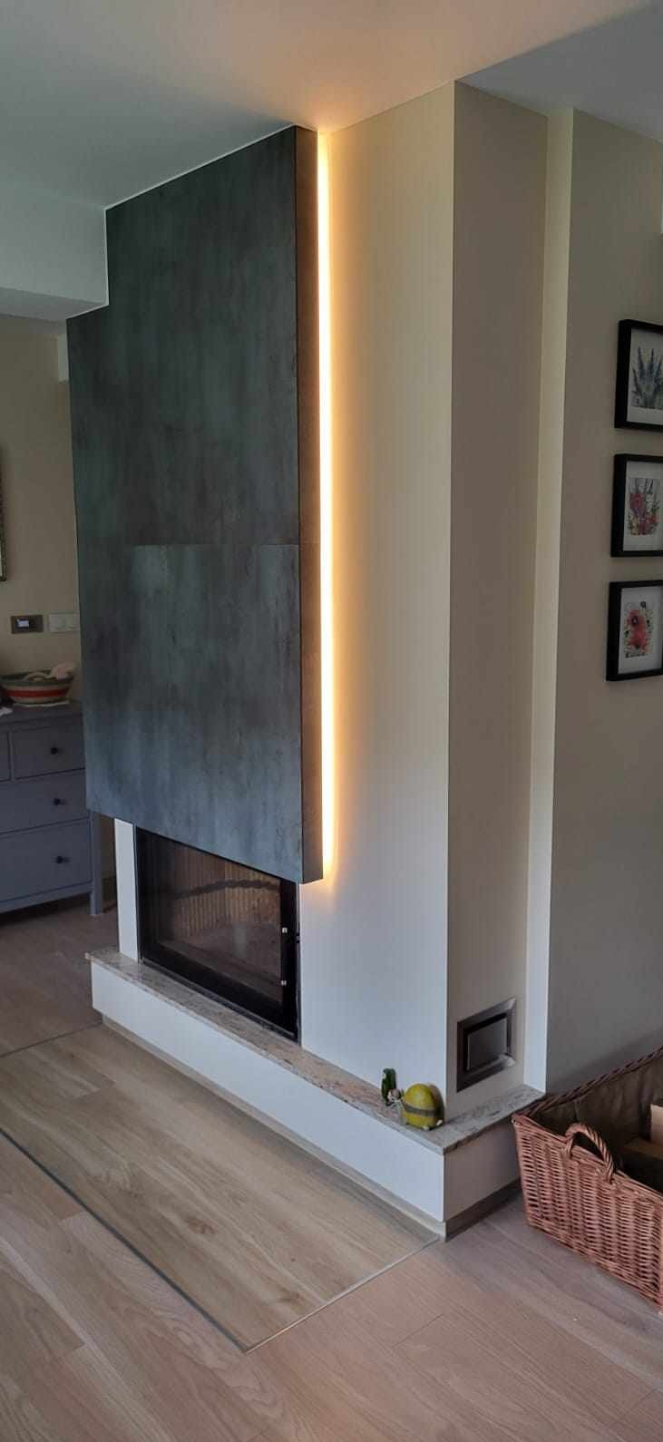 Nowoczesny kominek z szarymi płytami i pionowym oświetleniem LED. Estetyczne wykończenie wnętrza z dbałością o detale.