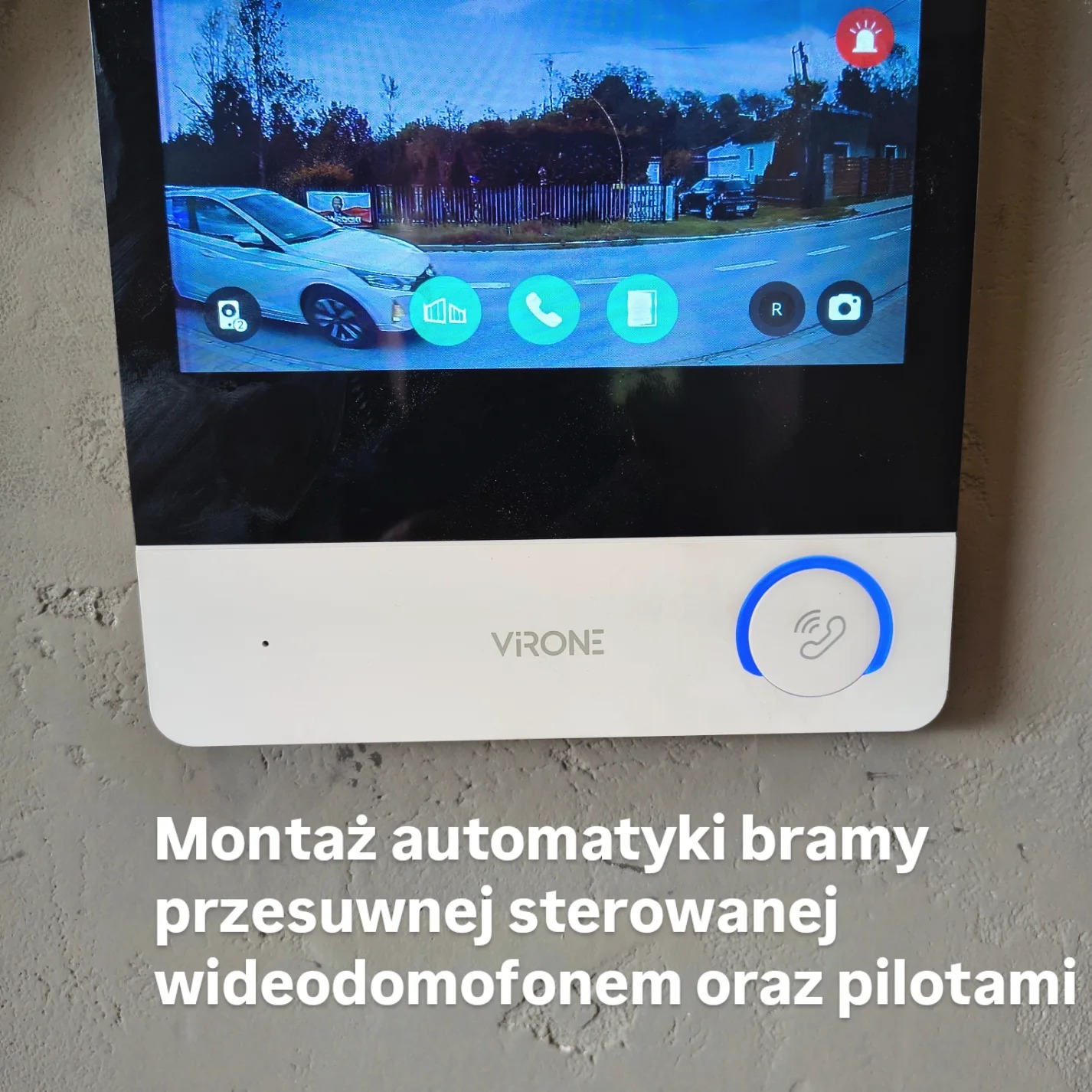 Ekran wideodomofonu VIRON z podglądem na ulicę i samochód. Widoczne przyciski sterowania i logo firmy. Montaż automatyki bramy przesuwnej.
