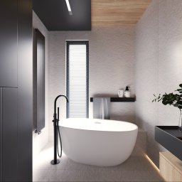 MIO HOME projekty i wykonanie pod klucz - Minimalistyczna łazienka: wolnostojąca wanna z czarną armaturą, jasne płytki imitujące kamień, wąskie okno z żaluzjami, drewniany akcent na suficie i subtelne oświetlenie LED.