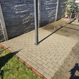 Czysty Ejber - Częściowo umyta kostka brukowa na posesji, widoczna różnica w czystości, cień osoby. Tło stanowi szary, kamienny mur i zieleń. Ujęcie z góry.