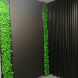 Maksym Nesterenko - Nowoczesna aranżacja ściany z pionowymi panelami i pasami zieleni w pomieszczeniu. Dekoracja wnętrza z elementami roślinnymi i ciemną kolorystyką.
