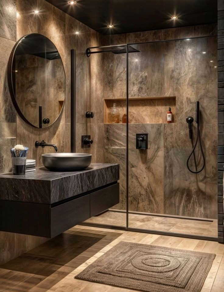 Nowoczesna łazienka w Legnicy z kabiną typu walk-in, okrągłym lustrem i kamienną umywalką. Ciepłe oświetlenie punktowe podkreśla marmurkowe płytki.