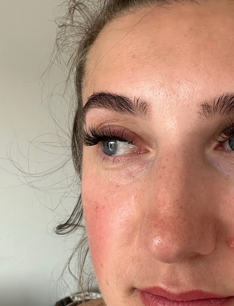 Zbliżenie na oko kobiety z wyraźnie podkreślonymi, długimi rzęsami i wyregulowanymi brwiami, prezentujące efekt zabiegu kosmetycznego.