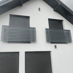 FusionWW - Biały dom z szarymi roletami i balkonami z poziomymi, szarymi panelami. Nowoczesny design z minimalistycznym oświetleniem zewnętrznym.