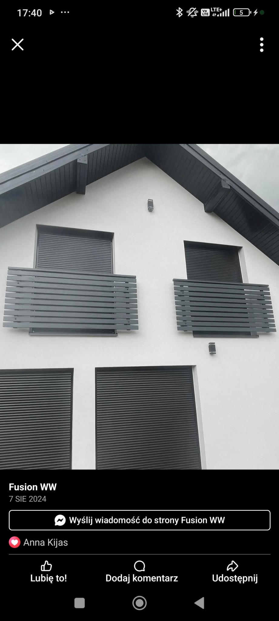 Biały dom z szarymi roletami i balkonami z poziomymi, szarymi panelami. Nowoczesny design z minimalistycznym oświetleniem zewnętrznym.