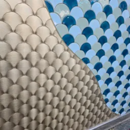 Mozaika w kształcie rybiej łuski, łącząca złote i niebieskie odcienie, ułożona na ścianie w Żarki-Letnisko. Dekoracyjne wykończenie wnętrz.