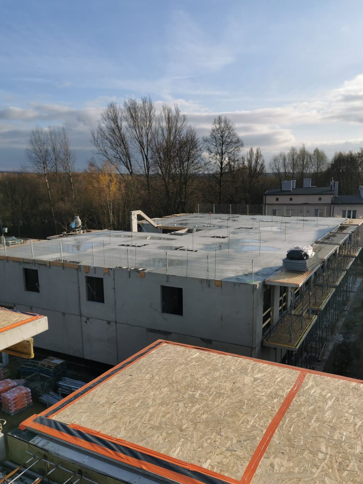 Stan surowy budynku wielorodzinnego w Dobrczu, widok z góry. Betonowy strop z zabezpieczeniami, szalunki balkonowe, częściowo widoczne ściany nośne.