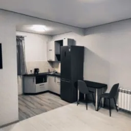 Wnętrze pokoju z aneksem kuchennym w odcieniach szarości i bieli. Widoczne meble kuchenne, stół z krzesłami, lodówka i grzejnik. Minimalistyczny design.