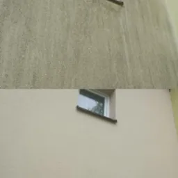 Elewacja budynku przed i po czyszczeniu, widoczne różnice w kolorze i usunięte zabrudzenia. Okno z białą ramą w kadrze.