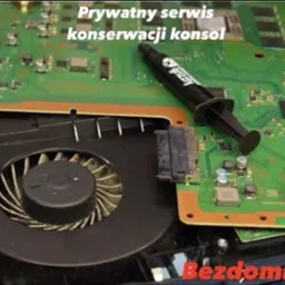 Otwarta konsola do gier z widocznym wentylatorem i pastą termoprzewodzącą, sugerująca konserwację lub naprawę sprzętu.
