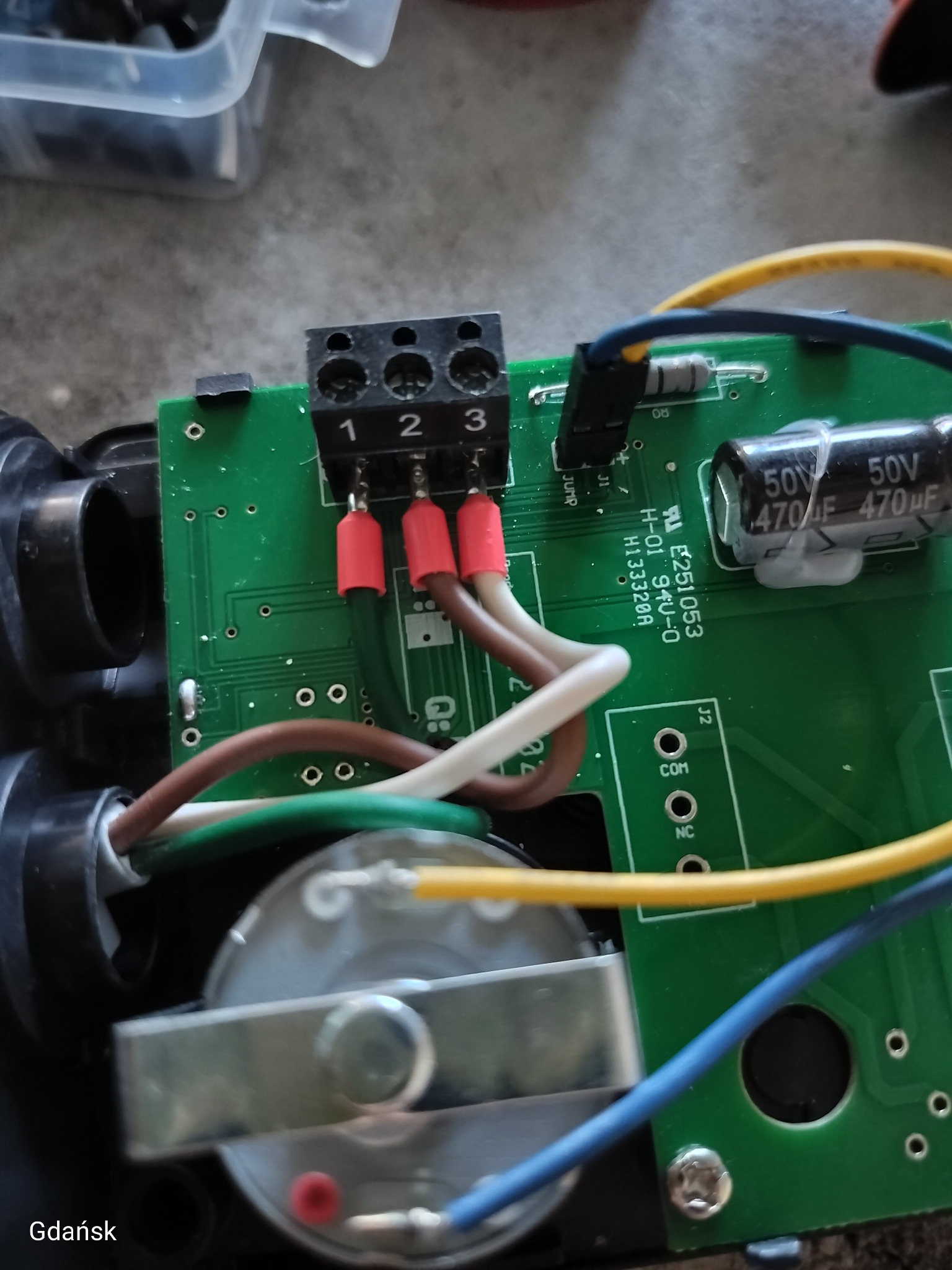 Zielona płytka drukowana z podłączonymi kablami o różnych kolorach (brązowy, biały, zielony, żółty, niebieski) do czarnej kostki z numerami 1, 2, 3.