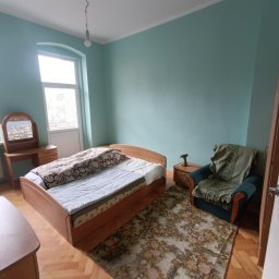 Oleh Tuz EUROBILD - Pokój z łóżkiem, fotelem i toaletką, ściany pomalowane na błękitno. Na szafce nocnej leży wiertarka. Parkiet ułożony w jodełkę.