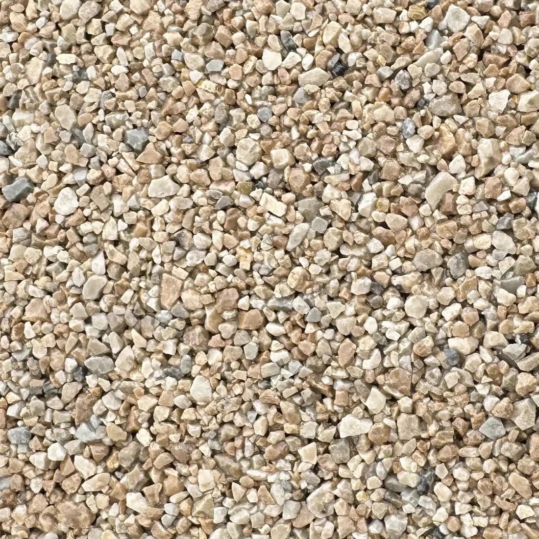 Beżowo-szare kruszywo marmurowe Paloma, drobne kamyczki o nieregularnych kształtach, wypełniające całą powierzchnię. Tekstura zbliżenie, oświetlenie naturalne.