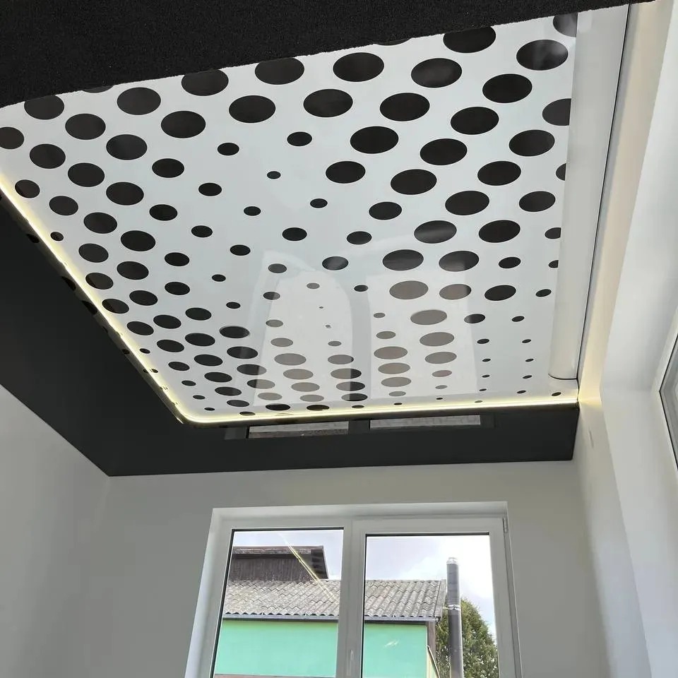Biały sufit z czarnymi kropkami i podświetleniem LED, widok z dołu, okno w tle. Nowoczesny design wnętrza.