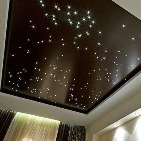 Ciemnobrązowy sufit z efektem gwiazd, drobne punkty świetlne imitują nocne niebo. Widok z dołu, fragment zasłon w tle.